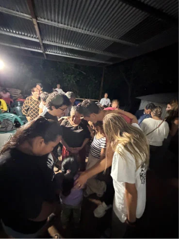 Adults and children gathered closely during an evening prayer