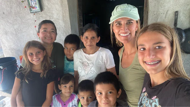 Adults and children smiling together for a photo outside a home